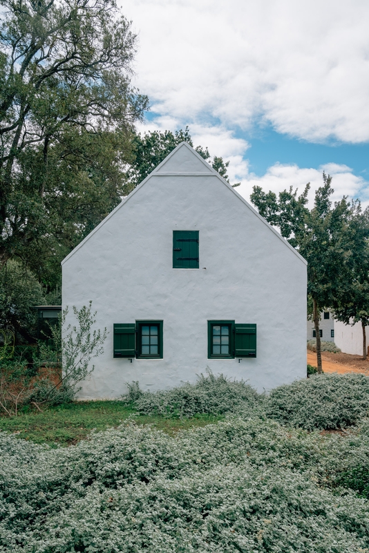 Whitewashed Cottage Among Green Trees