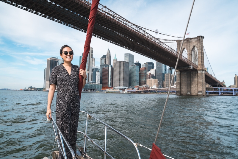 Woman on Sailboat Under Brooklyn Bridge