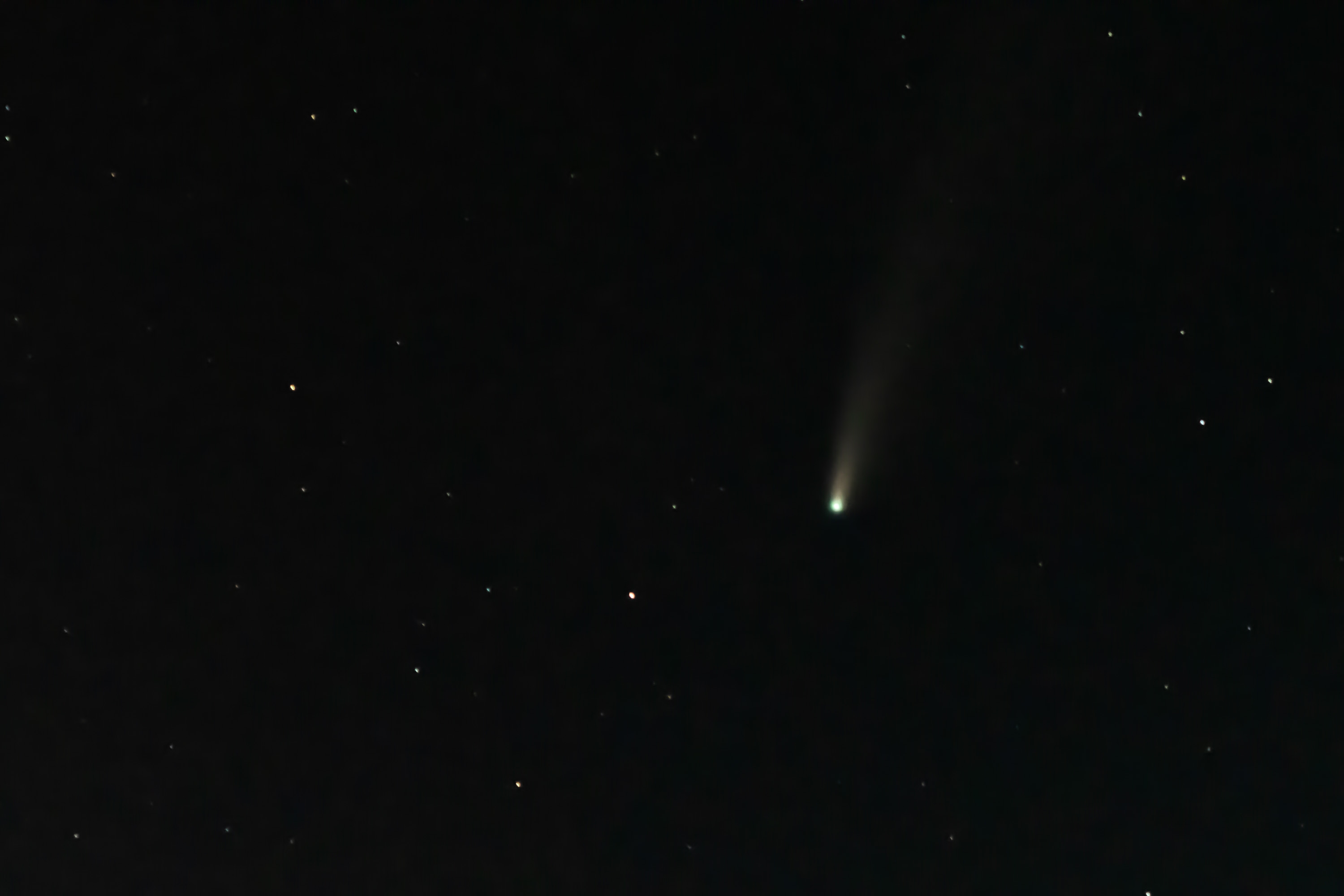 A bright comet with a luminous tail streaks across a dark night sky scattered with distant stars