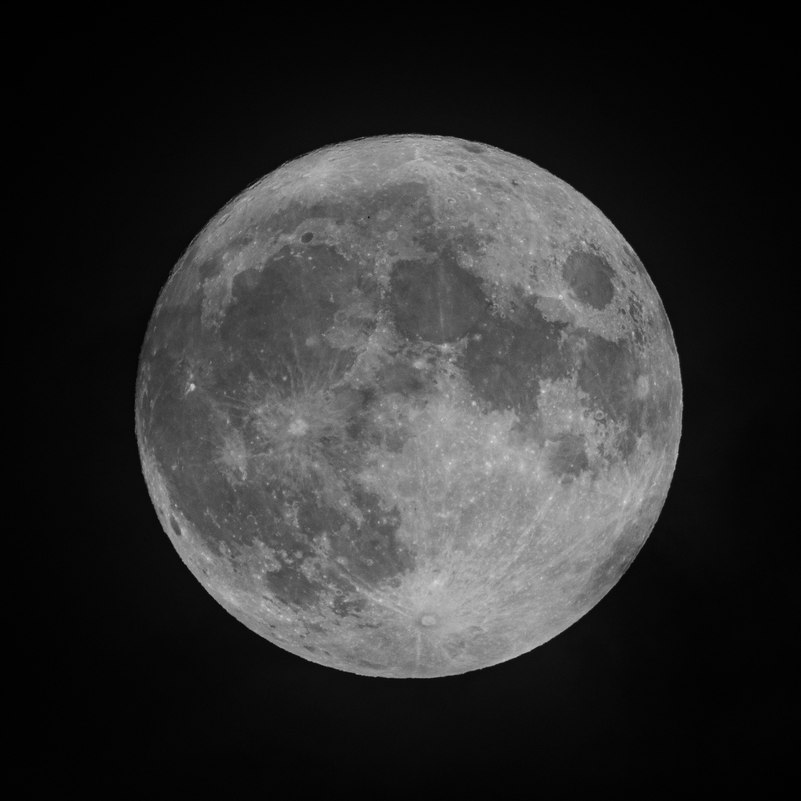 A full moon with detailed surface craters and maria displayed against a pure black night sky, captured with sharp clarity and high contrast