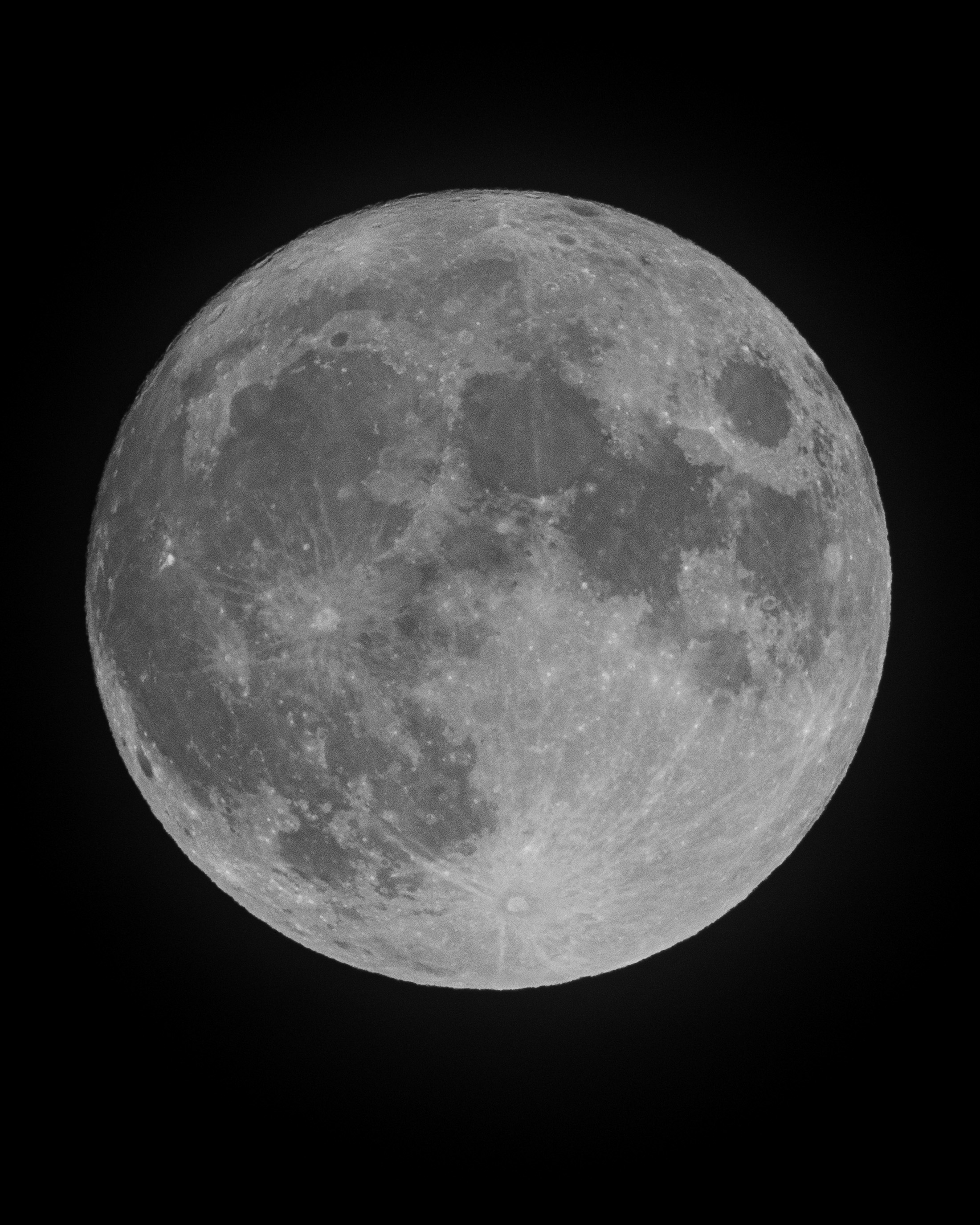 A fully illuminated moon dominates the frame against a black sky, its cratered and maria-marked surface rendered in shades of gray with fine detail visible across the entire sphere