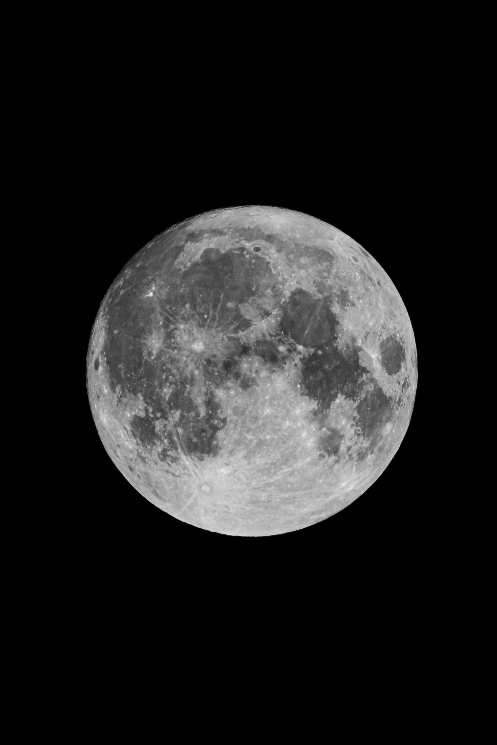 A full moon displaying detailed craters and maria against a pitch-black night sky, with sharp surface texture and bright highlights illuminating the lunar landscape